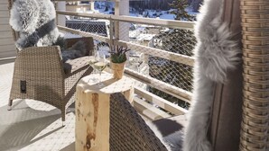 A balcony with wicker furniture, a potted plant, and a glass of wine. - AMERON Davos Swiss Mountain Resort (Davos)