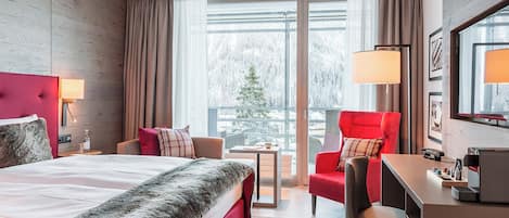 A hotel room with a bed, a desk, a chair, and a view of a snowy landscape.