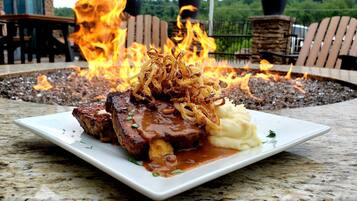 A plate of food with a fire pit in the background.