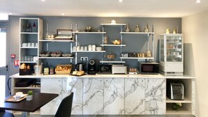 A modern kitchen with marble countertops, built-in shelves, and various appliances. - Hôtel Les Beaux Soleils (Osny)