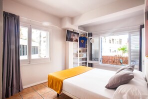 Quarto com cama, televisão numa estante e janela com vista para o exterior.