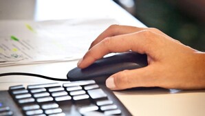 A hand using a computer mouse on a desk with a keyboard. - Ten Hostel (Ibiza Town)
