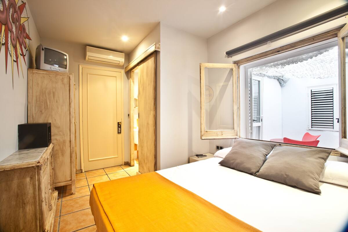 Ein Schlafzimmer mit Bett, Nachttisch und einem Fenster mit Blick.