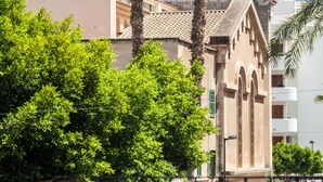A building with a beige facade, a balcony, and a palm tree in front. - Ten Hostel (Ibiza Town)