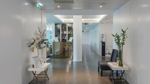 A modern hotel lobby with a clean, minimalist design, featuring a reception desk, seating area, and a glass partitioned room in the background. - Lux Fátima Park - Hotel, Suites & Residence (Ourem)