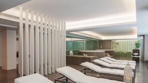 A modern spa room with multiple treatment beds, a reception area, and a glass-enclosed sauna. - Lux Fátima Park - Hotel, Suites & Residence (Ourem)