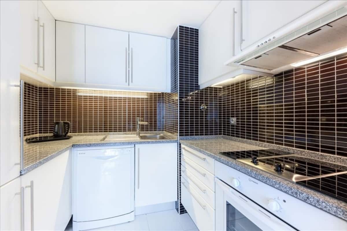Une cuisine moderne avec des armoires blanches, un lave-vaisselle intégré, une cuisinière et un four à micro-ondes.