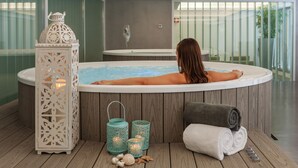 A spa area with a hot tub, decorative lanterns, and a towel on the floor. - Lux Fátima Park - Hotel, Suites & Residence (Ourem)
