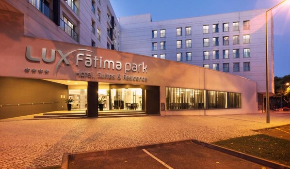 Entrada do Hotel Lux Fatima Park com um design moderno, apresentando grandes janelas e uma entrada acolhedora.