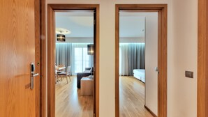 A hotel room with a wooden floor, a bed, a desk, and a chair. - Lux Fátima Park - Hotel, Suites & Residence (Ourem)