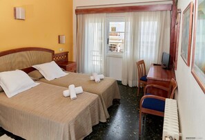 A hotel room with two beds, a desk, a chair, a TV, and a window with curtains. - Hostal Illes Pitiüses (Formentera)