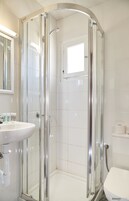 Un baño moderno con ducha de vidrio, lavamanos blanco y un inodoro.