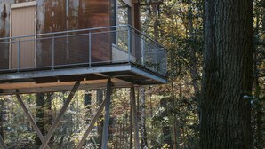 A treehouse with a metal balcony, surrounded by a forest. - V-Hotel (Bonn)