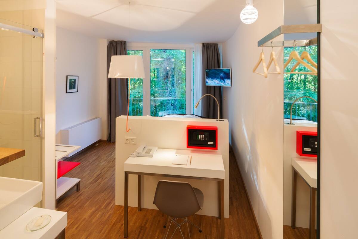 A modern hotel room with a desk, chair, and a TV mounted on the wall.