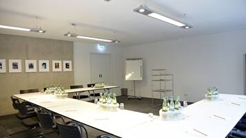 Et mødelokale med et langt bord, stole og en projektorskærm.