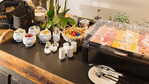 A buffet setup with various food items, a chef in the background, and a decorative orchid centerpiece. - V-Hotel (Bonn)