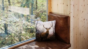 A wooden cabin with a built-in bench and a window overlooking a forest. - V-Hotel (Bonn)