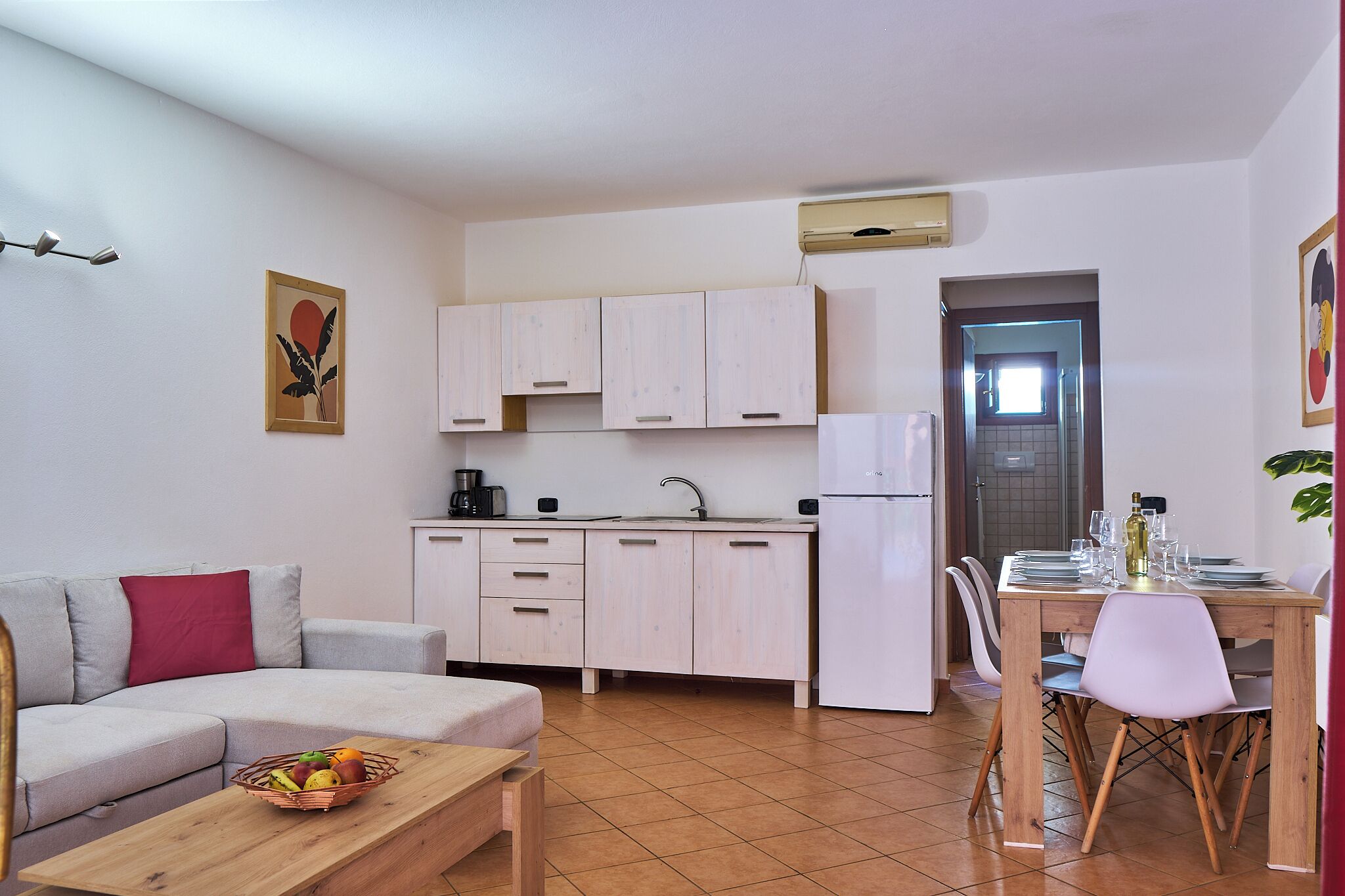 Un ambiente compatto con angolo cottura, zona pranzo e divano.