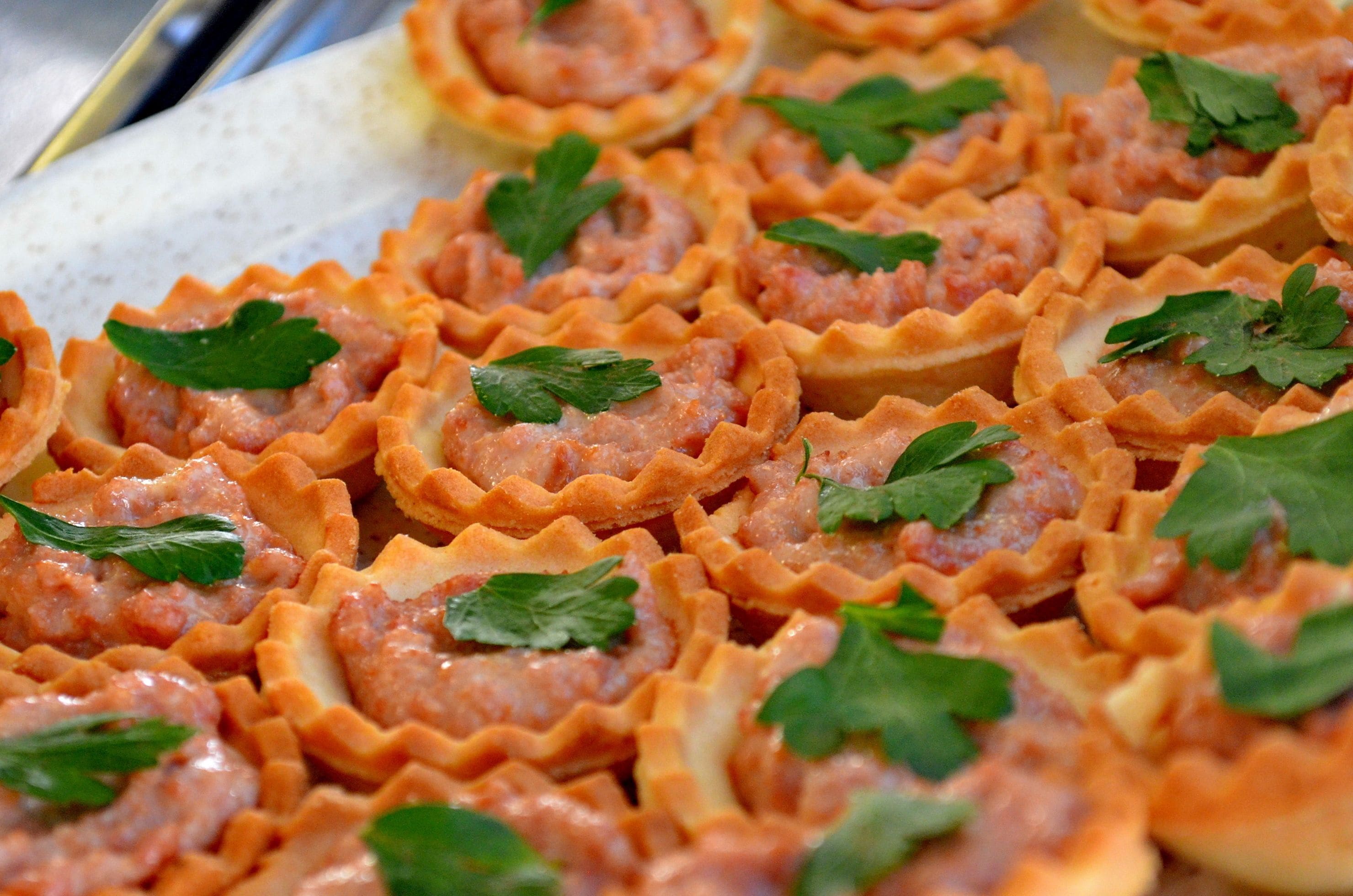Uma travessa de mini quiches decoradas com salsa.