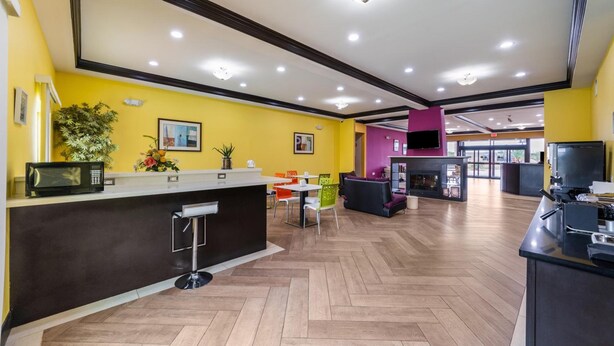 A modern hotel lobby with a reception desk, seating area, and a large TV screen. - Residency Suites - Cotulla (Cotulla)