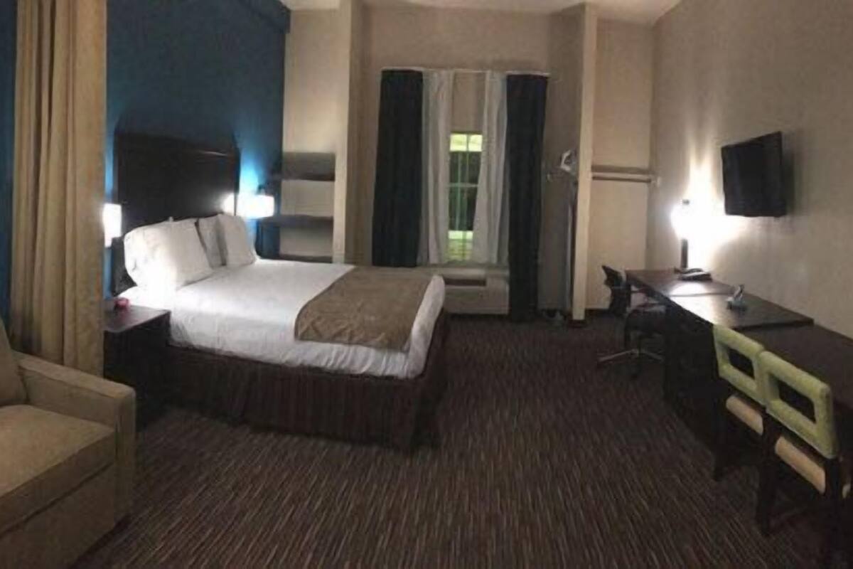 Une chambre d’hôtel avec un lit, un canapé, un bureau et une télévision.