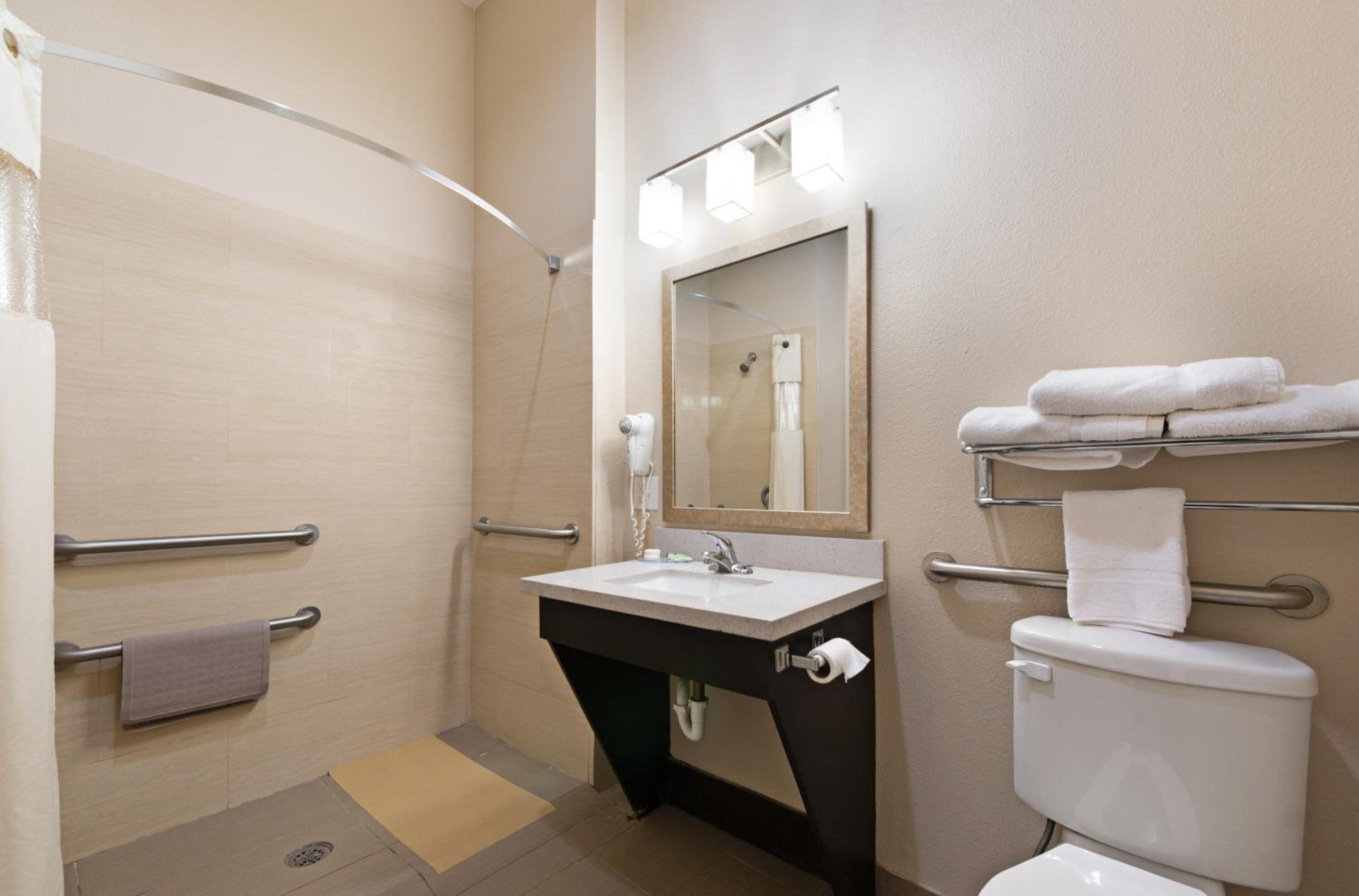 Un baño con ducha, lavabo, inodoro y toallero.