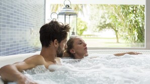 Una pareja en un jacuzzi con vistas a un jardín y un farol.