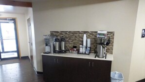 A reception area with a coffee station, a trash bin, and a door leading to another room. - Red Roof Inn Grand Junction (Grand Junction)