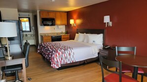 A hotel room with a bed, desk, chair, and kitchenette. - Red Roof Inn Grand Junction (Grand Junction)
