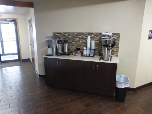 Un espace d’accueil avec un comptoir, des machines à café et une poubelle.