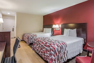 Une chambre d’hôtel avec deux lits, un bureau, une chaise et une petite table.