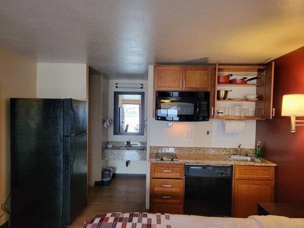 A compact kitchen with a refrigerator, microwave, sink, and wooden cabinets. - Red Roof Inn Grand Junction (Grand Junction)