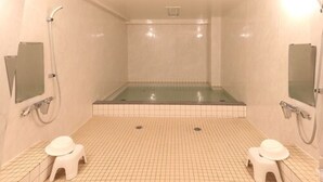 Un baño pequeño con azulejos, ducha, dos lavamanos y dos cabinas de inodoros.