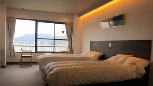 Habitación de hotel con dos camas, una silla, una ventana con vistas y un espejo en la pared.