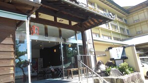 Un edificio con entrada de vidrio, mesas al aire libre y un letrero con caracteres japoneses.