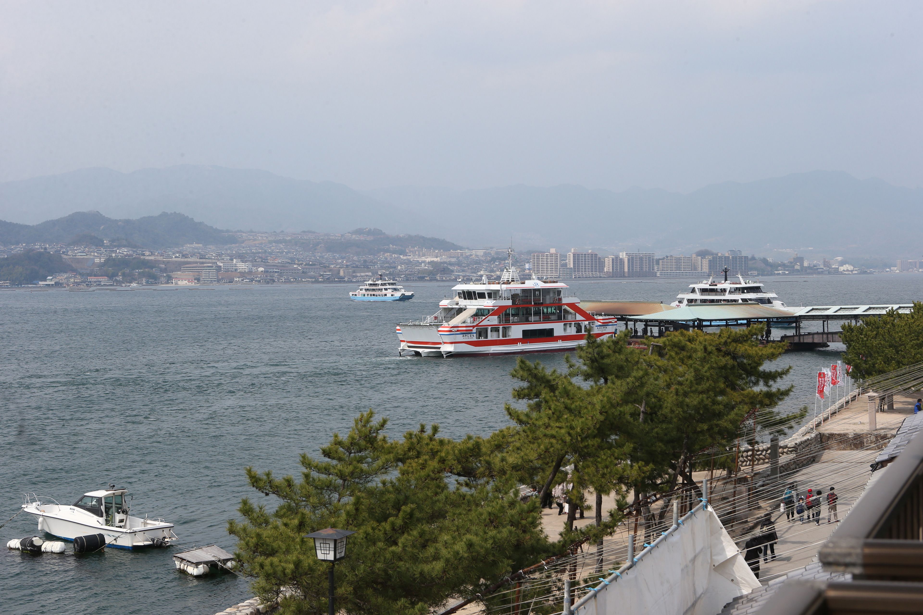 A waterfront view with boats docked, a pier, and a cityscape in the background.