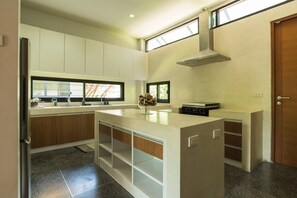 A modern kitchen with white cabinets, a central island, and a built-in oven.
