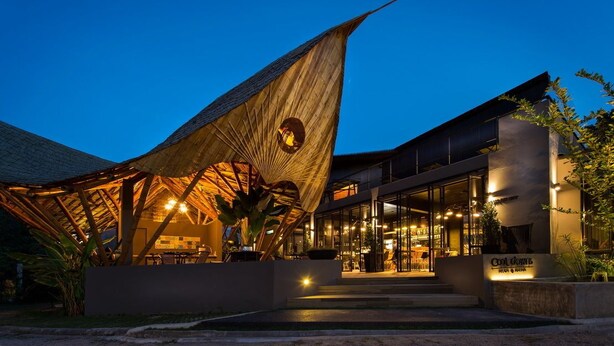 A modern building with a unique, curved roof structure and a glass entrance.