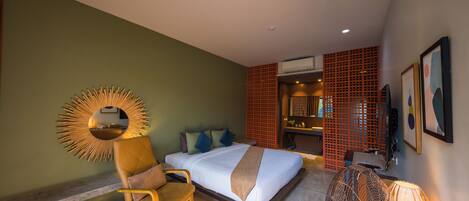 A hotel room with a bed, a chair, a fan, and a mirror on the wall.