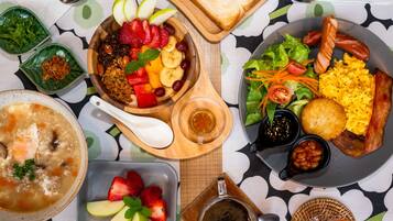 A table with various dishes including soup, salad, toast, and a plate with eggs, bacon, and sausages.