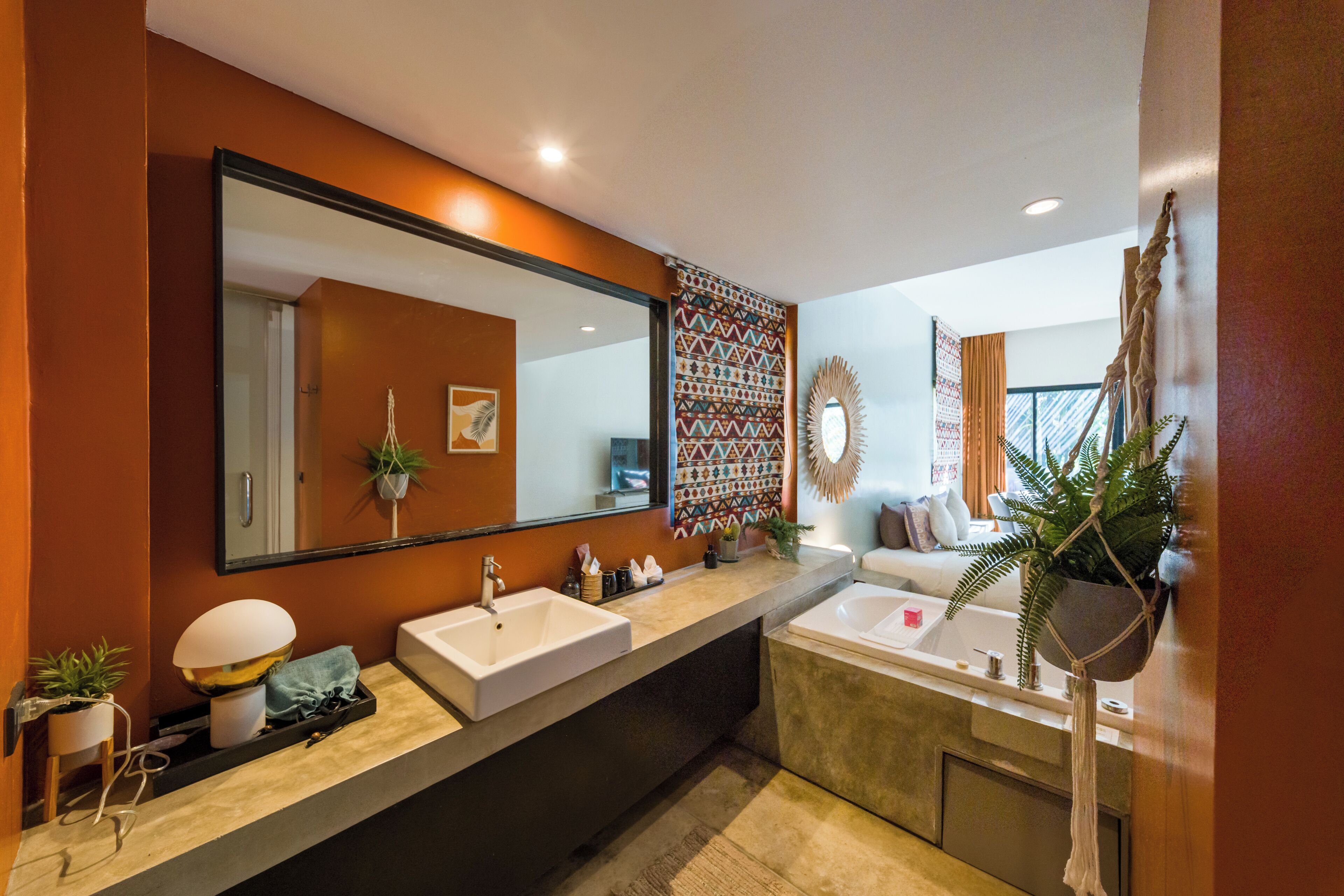A modern bathroom with two sinks, a bathtub, a large mirror, and a decorative wall panel.