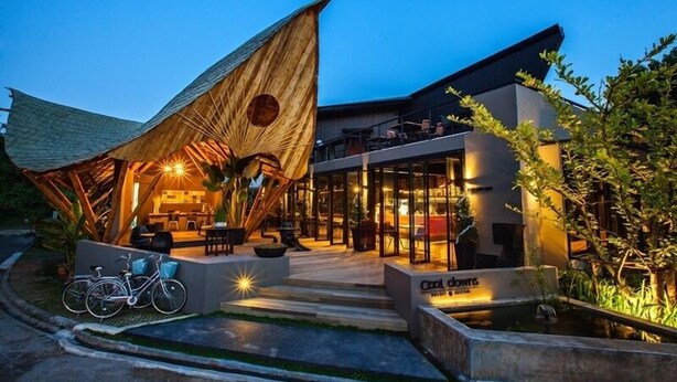 Un edificio moderno con un amplio patio abierto, una zona de estar cubierta y un letrero que dice 