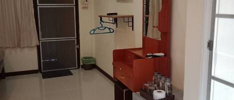 A hotel room with a sliding door, a red sink, a mirror, a small refrigerator, and a TV mounted on the wall.