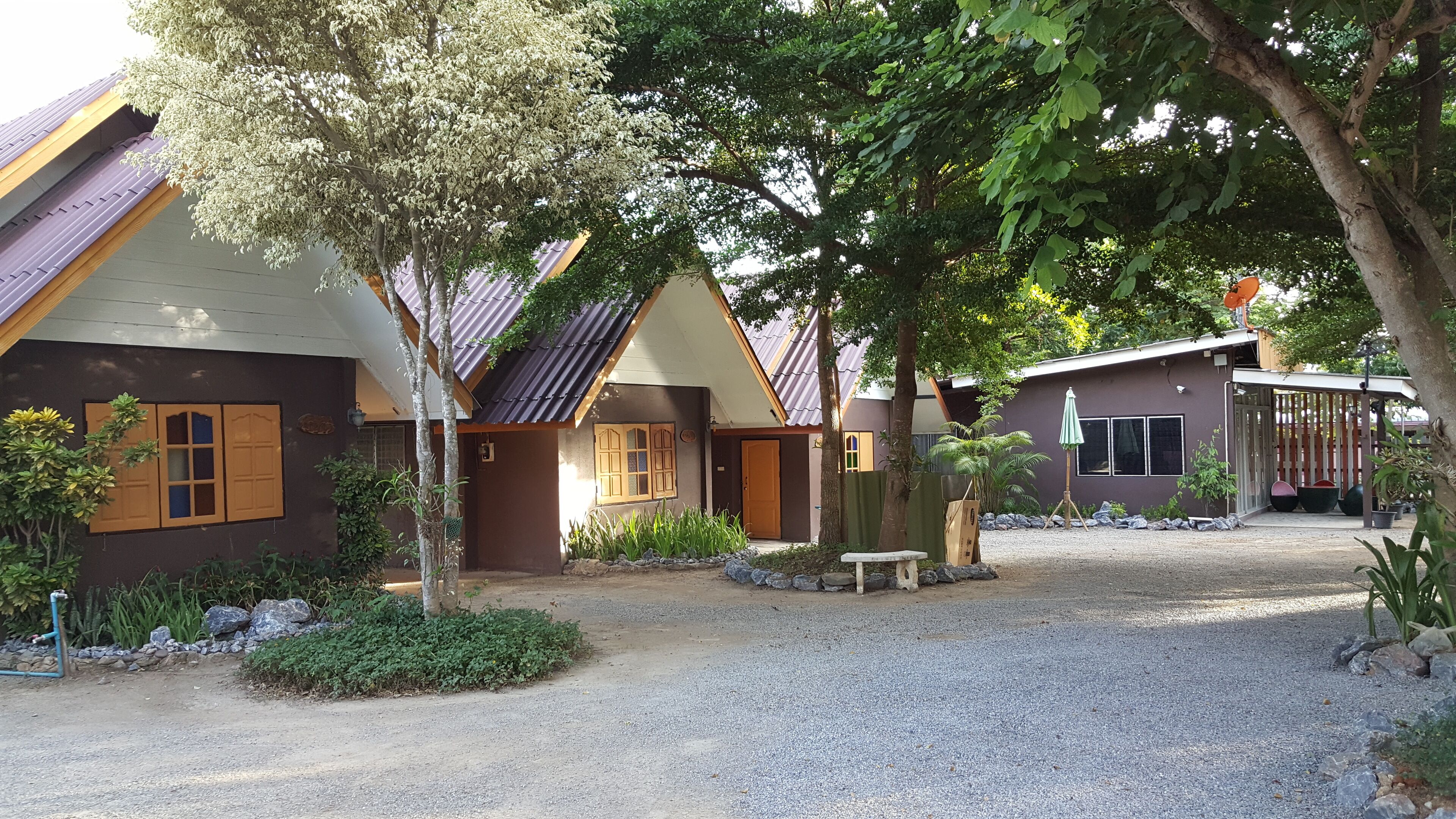 A residential area with houses, trees, and gravel paths.