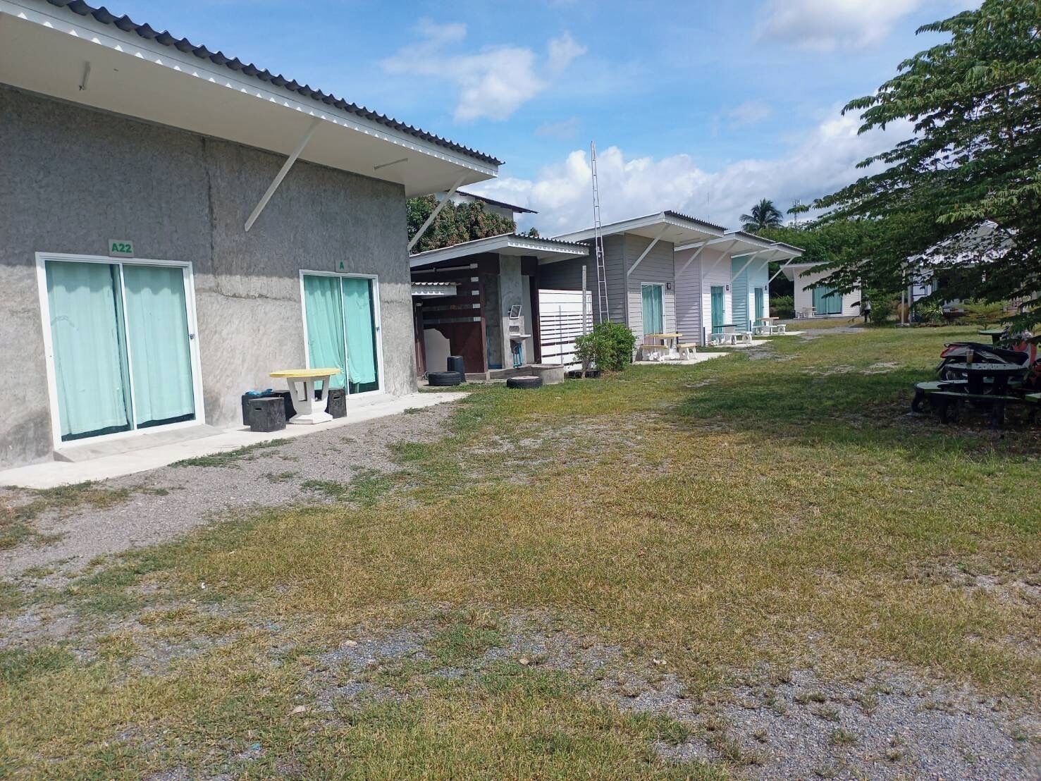 A row of single-story buildings with large windows and doors, a grassy area in front, and a clear sky.