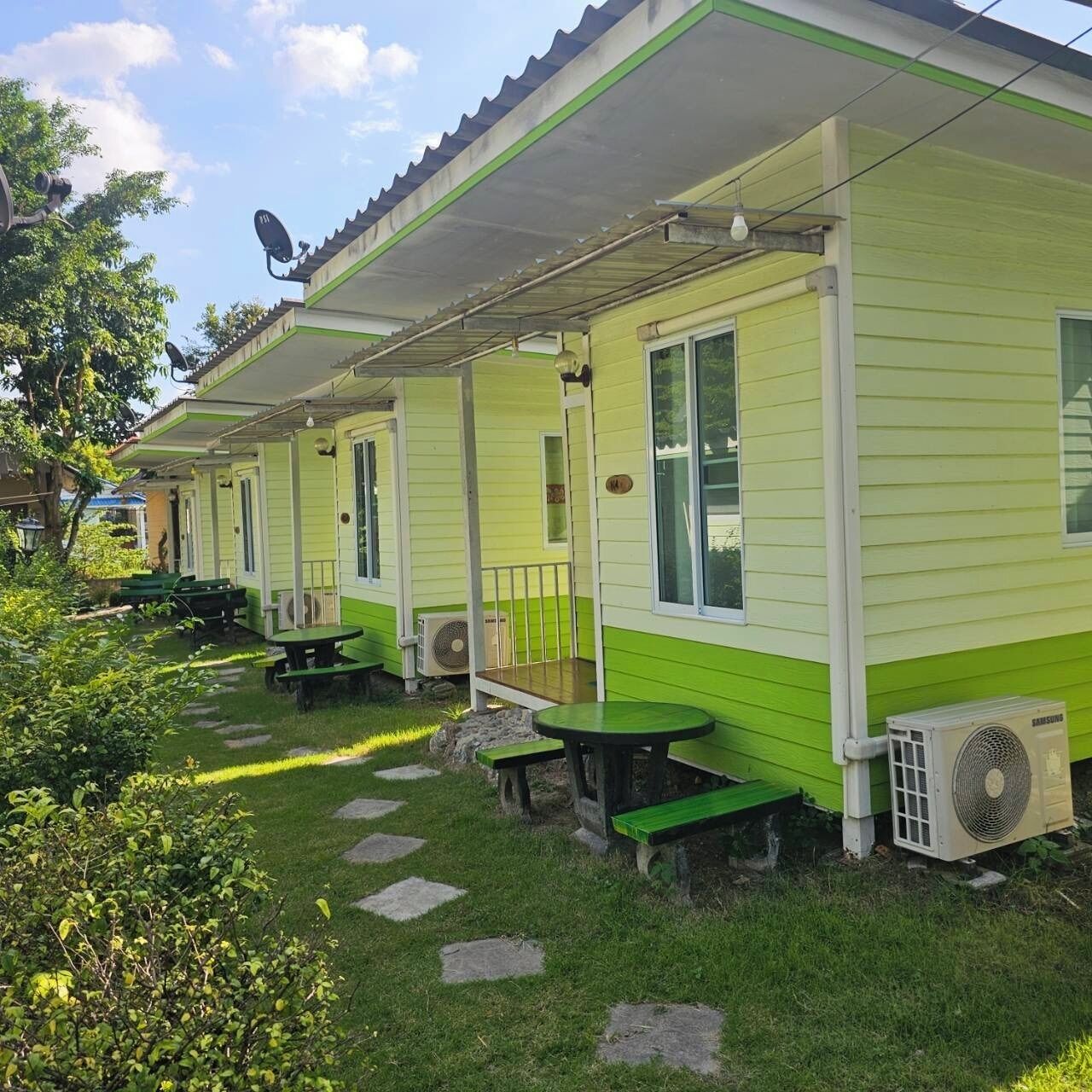 A row of green and white mobile homes with attached porches, outdoor seating, and air conditioning units.