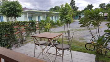 Un patio con una mesa y sillas, rodeado de follaje y un edificio al fondo.