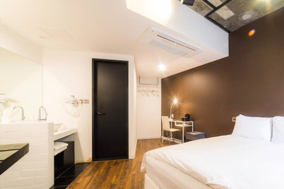 A modern hotel room with a bed, a desk, and a bathroom.