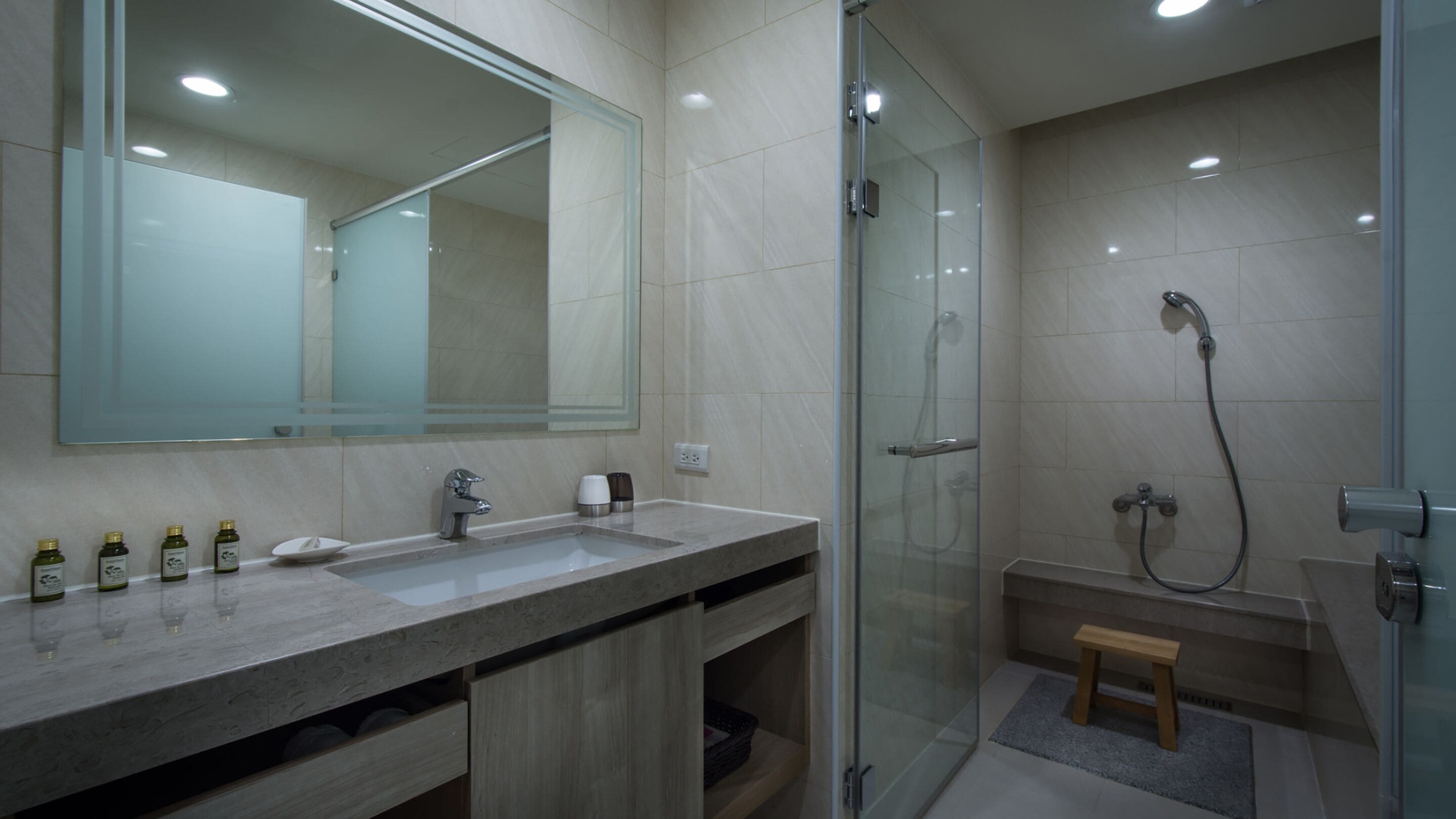 A modern bathroom with a glass-enclosed shower, a large mirror, and a marble sink.