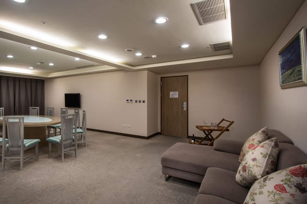 A conference room with a round table, chairs, a sofa, and a television.